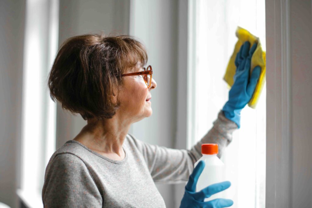 Frau putzt im Rahmen einer Umzugsreinigung die Fenster